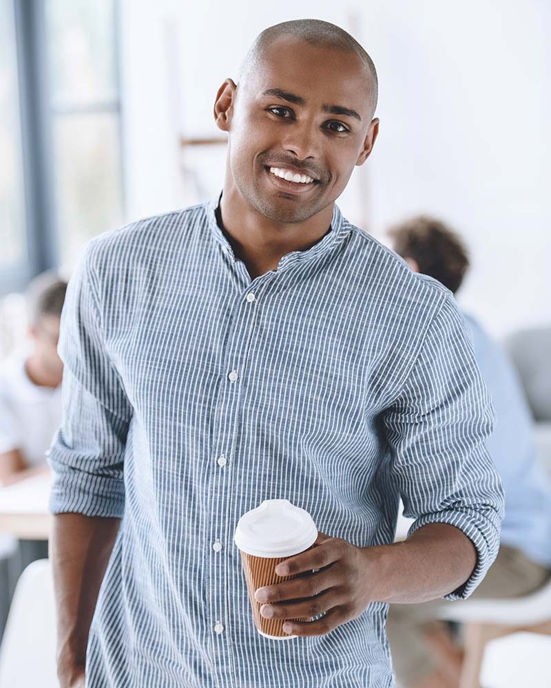 portrait of smiling african american businessman with coffee to go in office