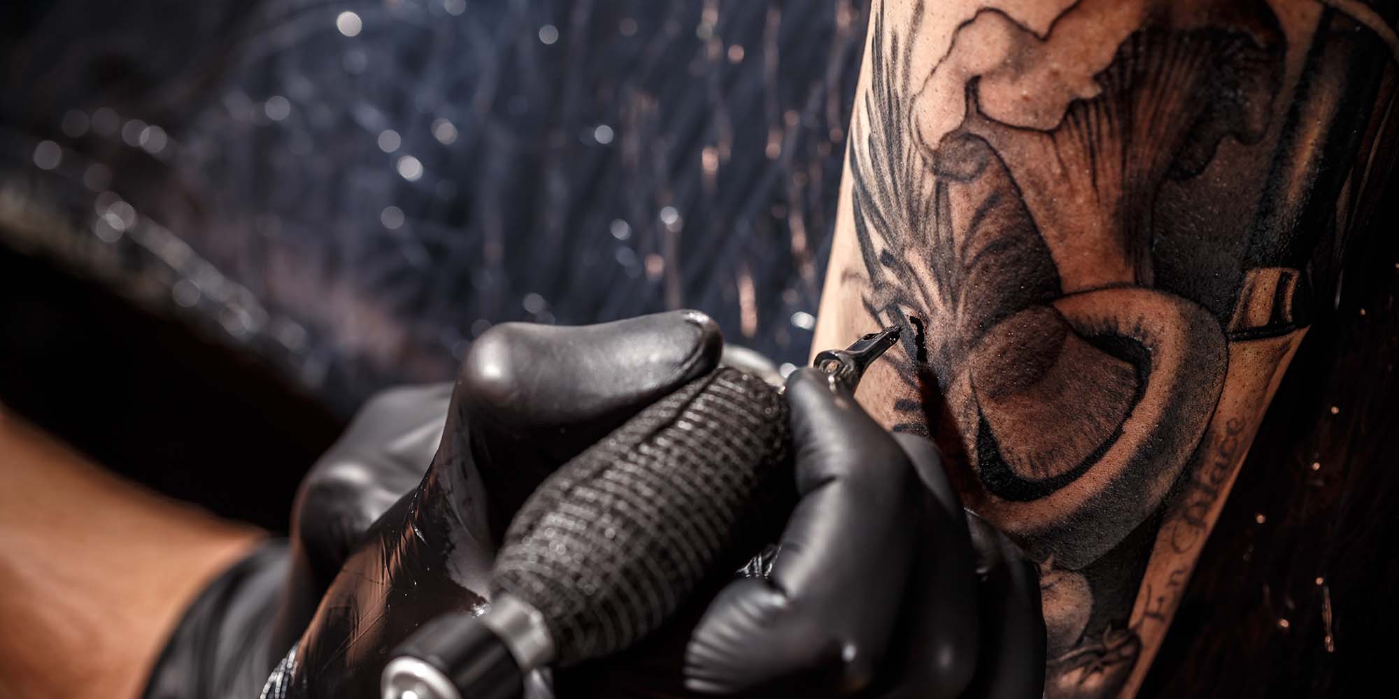 Close up image of the tattoo artist makes a tattoo on a man arm.