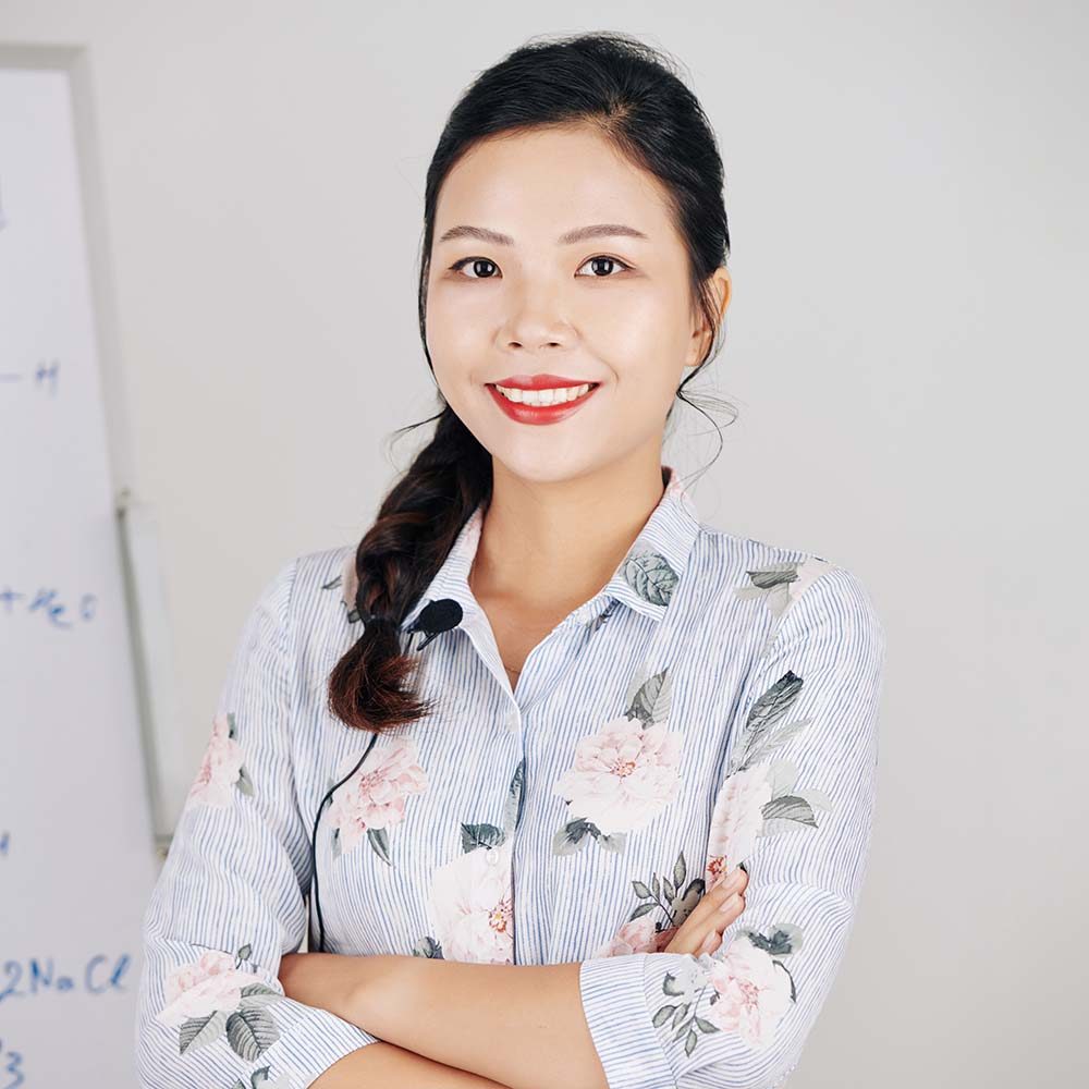 Portrait of pretty smiling Vietnamese science teacher standing with arms crossed