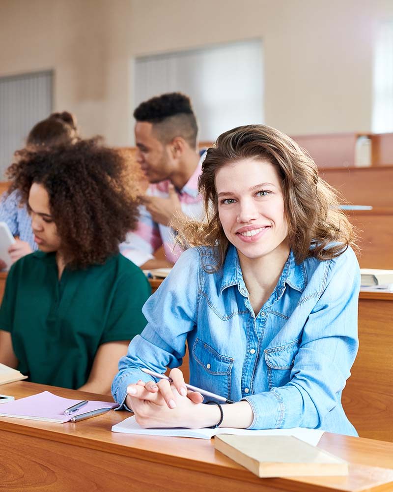 Smiling female student sitting at seminar at university